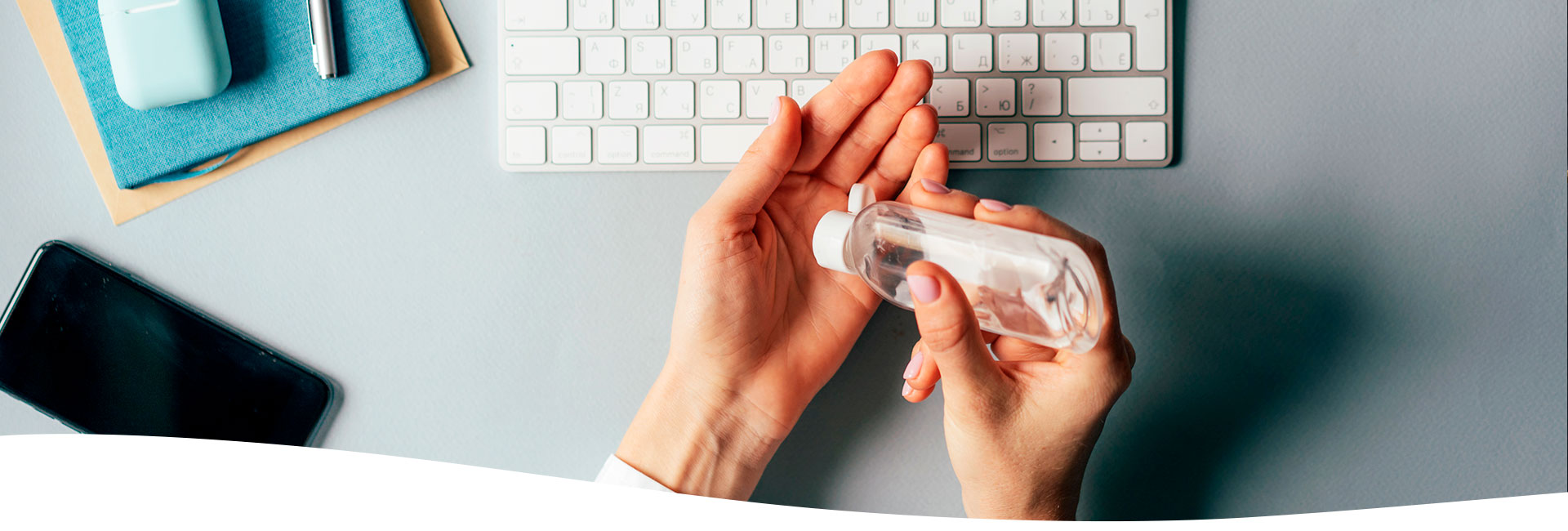 Manos de una mujer utilizando gel antibacterial sobre su escritorio