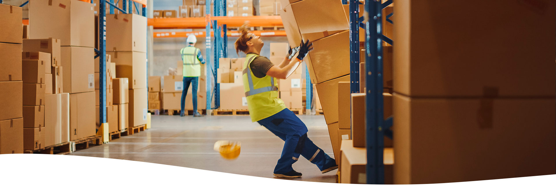 Trabajador de un almacén cayendo por intentar sujetar unas cajas